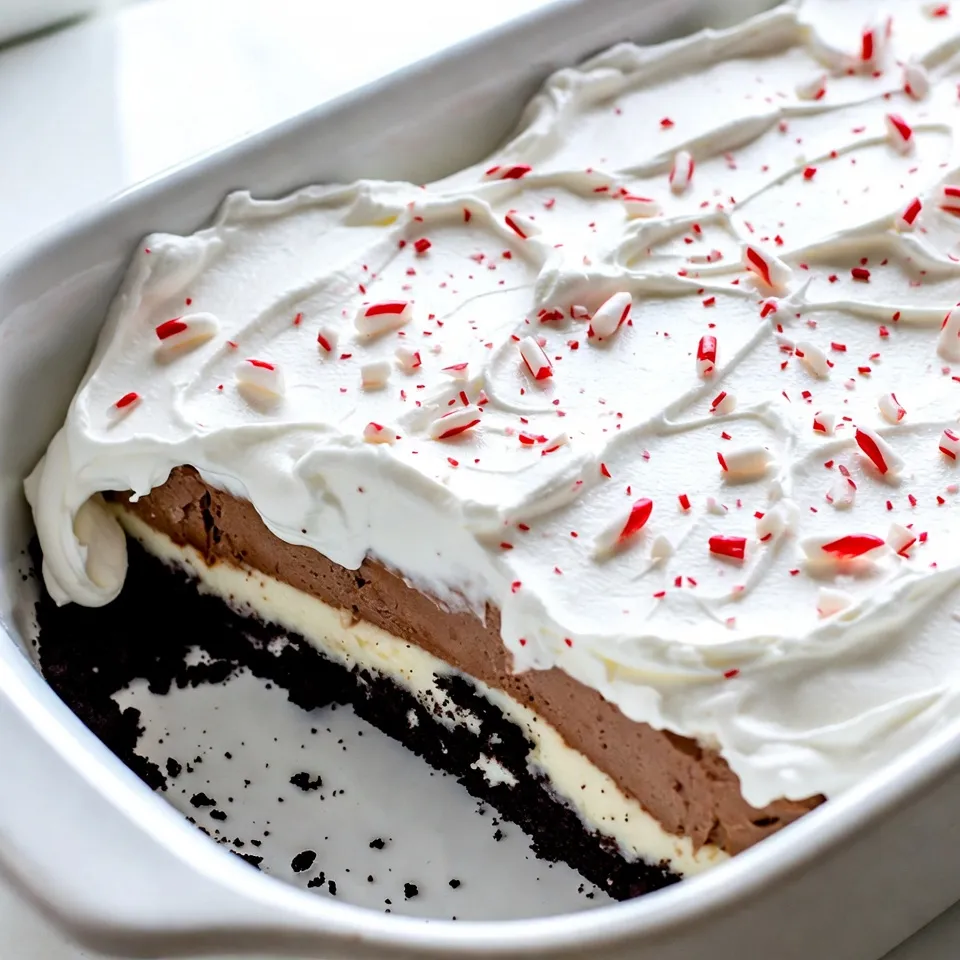 To make your No-Bake Christmas Oreo Lasagna, gather these ingredients: - 2 packs of Oreo cookies (about 36 cookies) - 1/2 cup unsalted butter, melted - 2 cups cream cheese, softened - 1 cup powdered sugar - 2 cups Cool Whip (whipped topping) - 1 teaspoon vanilla extract - 1 cup milk - 1 box (3.9 oz) instant chocolate pudding mix - 1 box (3.9 oz) instant vanilla pudding mix - 1/2 cup crushed peppermint candies (for garnish) Each ingredient plays a key role in this dessert. The Oreo cookies form the base, giving a rich chocolate flavor. The melted butter helps bind the cookie crumbs together. Cream cheese adds a creamy layer, while powdered sugar sweetens it up. Cool Whip creates a light and fluffy texture. The vanilla extract enhances the flavor, and milk helps prepare the pudding mixes. The chocolate and vanilla puddings add layers of taste and contrast. Finally, crushed peppermint candies give a festive touch on top. By using high-quality ingredients, you will ensure the best flavor. Always taste as you go! Enjoy the process of making this delightful dessert. {{ingredient_image_2}} To start, you need two packs of Oreo cookies. Place them in a food processor. Pulse the cookies until you get fine crumbs. Next, melt half a cup of unsalted butter. In a bowl, mix the cookie crumbs with the melted butter. It should feel like wet sand. Press this mixture into a 9x13 inch baking dish. Make sure the crust is even and firm. Now, grab two cups of softened cream cheese. Place it in a large bowl. Add one cup of powdered sugar to the cream cheese. Use an electric mixer to blend until smooth. Gently fold in one cup of Cool Whip. Make sure there are no lumps. Spread this cream cheese mix over your Oreo crust. For the pudding layers, you need chocolate and vanilla pudding mixes. In two bowls, prepare each pudding as the package says. Use two cups of milk for each flavor. Stir until combined. Let it sit for a few minutes to thicken. Once ready, pour the chocolate pudding over the cream cheese layer. Then, add the vanilla pudding on top. Take the remaining Cool Whip and spread it over the pudding layers. Use a spatula to make it smooth and even. This will create a nice finish for your dessert. Now, cover the baking dish with plastic wrap. Place it in the fridge. Let it chill for at least four hours. This helps the layers set well. Before serving, sprinkle crushed peppermint candies on top. This adds a festive touch. Cut the dessert into squares and serve it to your guests. Enjoy the smiles! To make a great Oreo crust, start with good quality Oreos. Use a food processor to crush them into fine crumbs. Mix these crumbs with melted butter. It should feel like wet sand. Press this mix firmly into the bottom of your baking dish. Make sure it is even. This helps the crust hold together well. For the cream cheese layer, use softened cream cheese. This makes it easy to mix. Combine it with powdered sugar in a bowl. Beat it until smooth and creamy. Then, fold in Cool Whip gently. This keeps the mix light and fluffy. Spread this layer evenly over the crust. It adds a rich taste to your dessert. When making the pudding layers, follow the package directions. Use cold milk for both chocolate and vanilla puddings. Stir until mixed and let them sit. This helps them thicken. Carefully pour the chocolate pudding over the cream cheese layer. Then, add the vanilla pudding on top. This creates a lovely, layered look. To add a festive touch, sprinkle crushed peppermint candies on top. This gives a great crunch and flavor. You can also use extra Cool Whip for a nice finish. For a special touch, serve each piece on holiday plates. Add a sprig of mint or a mini candy cane beside each slice. This makes your dessert look even more inviting. Pro Tips Use Fresh Ingredients: Always use fresh cream cheese and Cool Whip for the best texture and flavor in your lasagna. Chill Time is Key: Allow the lasagna to chill for a full 4 hours or overnight for the layers to set perfectly. Customizable Flavors: Experiment with different flavors of pudding or add layers of fruit for a unique twist on this classic dessert. Presentation Matters: Use a sharp knife for clean cuts and serve on festive plates to elevate your dessert's appearance. {{image_4}} You can change the cookies in this Oreo lasagna. Try using mint Oreos for a fresh twist. Golden Oreos can give a lighter flavor. You could even use gluten-free Oreos to fit your needs. Each type will change the taste and fun of this dessert. While chocolate and vanilla are classic, feel free to mix it up! Try butterscotch pudding for a sweet layer. Strawberry pudding can add a fruity touch. You can even use cookies and cream pudding for extra Oreo flavor. Each option offers a new and exciting taste in every bite. To make this dessert vegan, swap cream cheese for vegan cream cheese. Use coconut whipped cream instead of Cool Whip. Choose gluten-free Oreos to keep it safe for gluten-free eaters. With these changes, everyone can enjoy this festive treat! To keep your No-Bake Christmas Oreo Lasagna fresh, cover it tightly. Use plastic wrap or foil to seal the dish. Place it in the fridge. This dessert lasts for about 3 to 4 days. If you notice any change in texture or smell, it's best to toss it. Freezing this dessert is also possible. First, cut it into squares. Wrap each piece in plastic wrap. Then place them in an airtight container. This way, they won't get freezer burn. You can freeze the lasagna for up to 2 months. When you're ready to eat, let it thaw in the fridge overnight. This dessert is best served cold, so reheating is not needed. If you prefer it slightly soft, let it sit at room temperature for about 10 to 15 minutes. This will help it become creamy again without losing its charm. Enjoy each delightful bite! You can store No-Bake Christmas Oreo Lasagna in the fridge for up to 5 days. Just make sure it is covered well with plastic wrap. This keeps it fresh and tasty. The layers stay firm and the flavors blend well over time. Yes, you can use low-fat ingredients. Swap regular cream cheese for low-fat cream cheese. Use light Cool Whip too. The taste might change slightly, but it will still be delicious. Just remember, it might not be as rich and creamy, but it will still satisfy your sweet tooth. Absolutely! You can prepare the layers a day or two ahead. Just keep each layer stored separately in the fridge. When you're ready, layer them together and chill. This saves time on busy days and makes serving easier. If you need a substitute for Cool Whip, use heavy whipping cream. Whip it until stiff peaks form. You can also use homemade whipped cream. Just add a little sugar to sweeten it. Both options will work well and keep your dessert creamy and light. This blog covered how to make a No-Bake Christmas Oreo Lasagna. We discussed the ingredients, like Oreo cookies and cream cheese. You learned step-by-step instructions for each layer, from the crust to the topping. Tips helped ensure perfect layers and garnishing ideas added flair. We also explored variations and storage options to keep your dessert fresh. In the end, this simple treat brings joy and is easy to share. Enjoy making it for your friends and family this season!